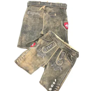 Zwei Paar traditionelle Schweizer Lederhosen mit Stickereien und Gürteldetails. Ein Paar trägt den Schriftzug Eidgenoss und beide zeigen ein rotes Schild mit einem weißen Kreuz, dem Symbol der Schweiz.