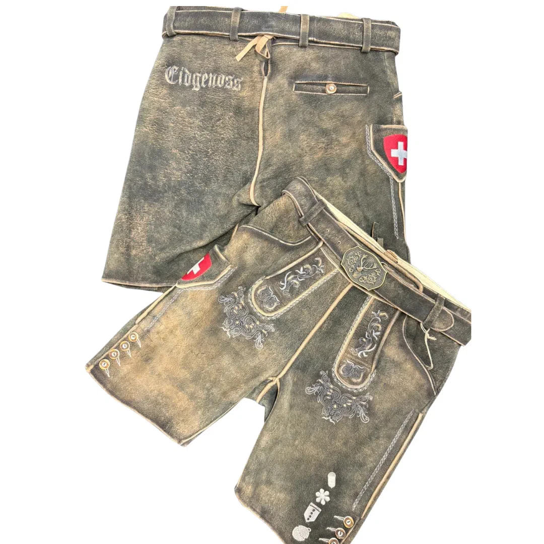 Zwei Paar traditionelle Schweizer Lederhosen mit Stickereien und Gürteldetails. Ein Paar trägt den Schriftzug Eidgenoss und beide zeigen ein rotes Schild mit einem weißen Kreuz, dem Symbol der Schweiz.