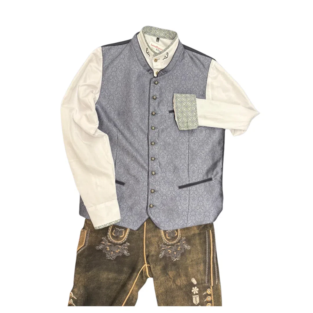 Ein traditionelles bayerisches Outfit mit einem weißen, langärmeligen Hemd, einer grauen, gemusterten Weste mit Knöpfen und einer braunen Lederhose mit Stickereien, alles ordentlich auf einem weißen Hintergrund angeordnet.