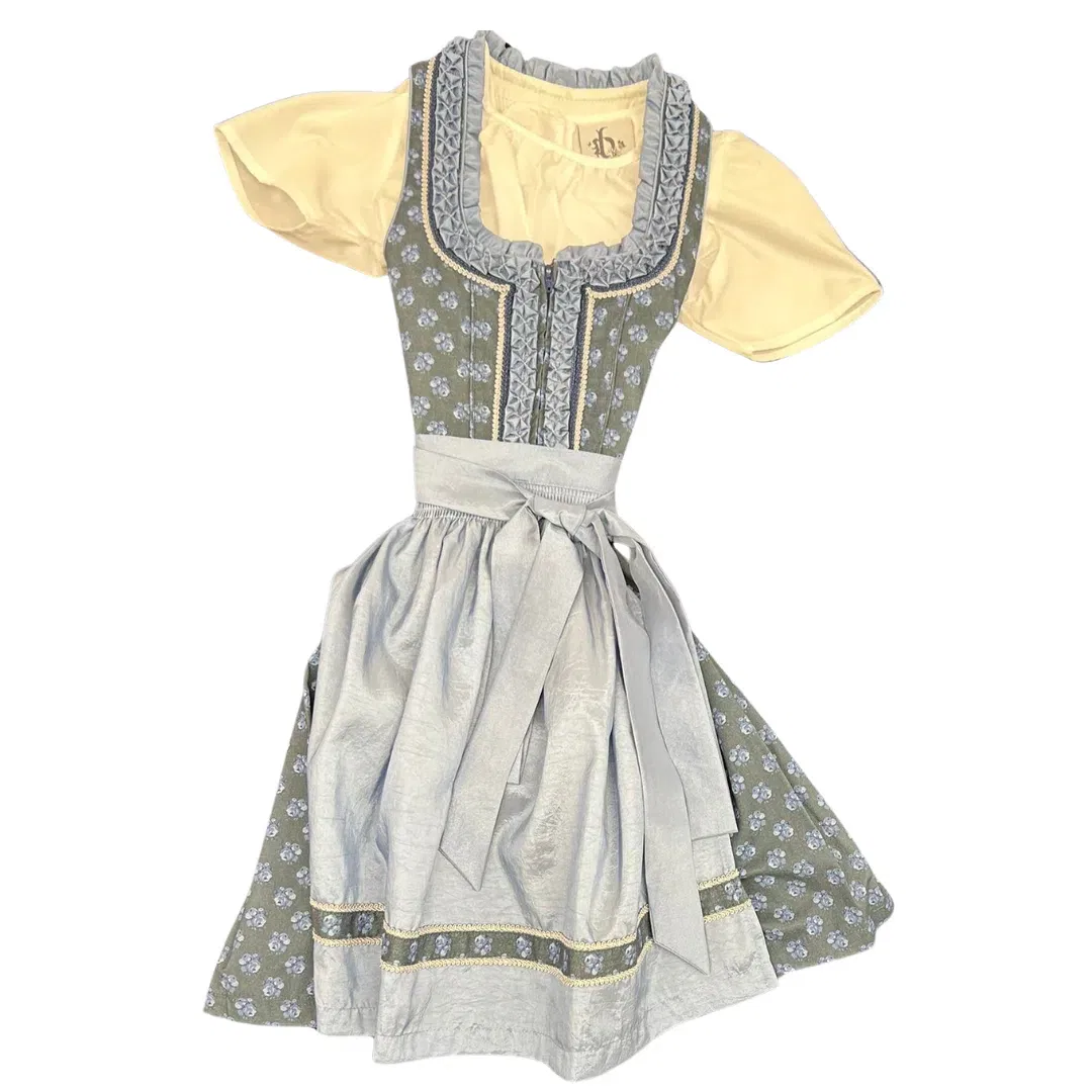 Ein traditionelles Dirndlkleid mit hellgelber Bluse, grauem Mieder und Rock mit blauem Blumenmuster und einer passenden grauen Schürze, die in der Taille gebunden wird. Das Kleid hat eine dekorative Borte um den Halsausschnitt.